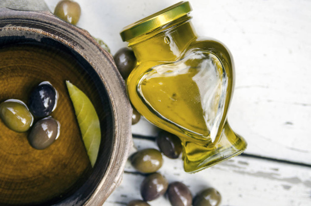 Olive oil in wooden brown pot with olives fruit.Extra virgin oil and green olives. Flat lay view - Photo, Image