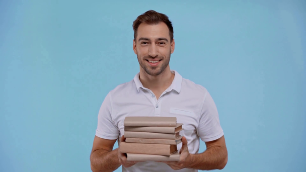 χαμογελαστός άνδρας κρατώντας βιβλία απομονωμένα στο μπλε - Πλάνα, βίντεο