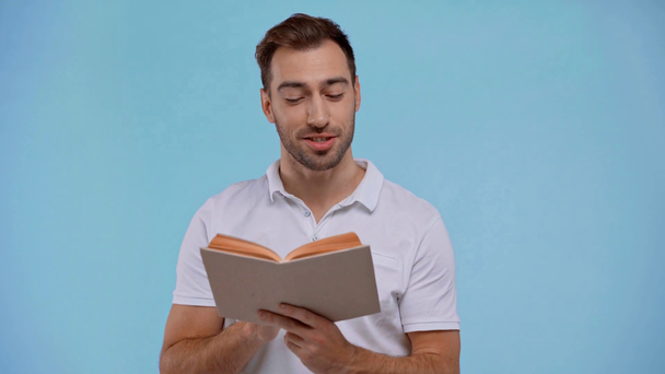 усміхнений чоловік читає книгу ізольовано на синьому
 - Кадри, відео