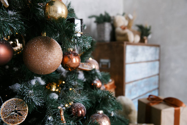Złote ozdoby świąteczne z cytrusami, piernikami i cynamonem na choince w domowym wnętrzu - Zdjęcie, obraz
