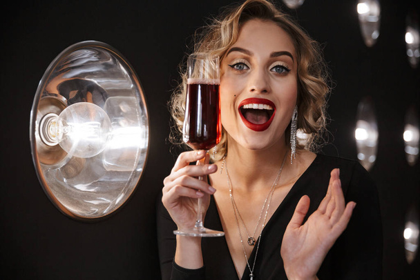 Image of joyful woman wearing elegant dress holding glass of red - Photo, image