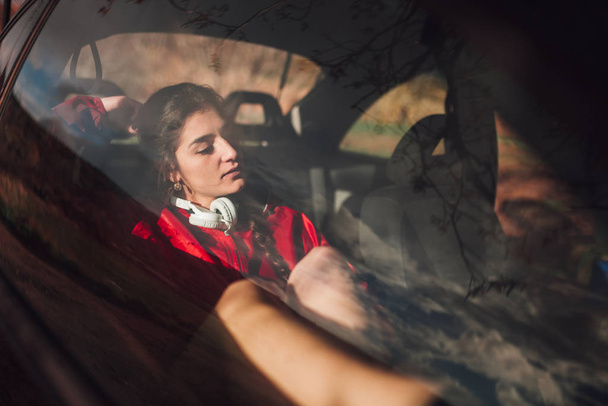 Egy fiatal nő menedéket keres egy kocsiban, amíg esik. - Fotó, kép