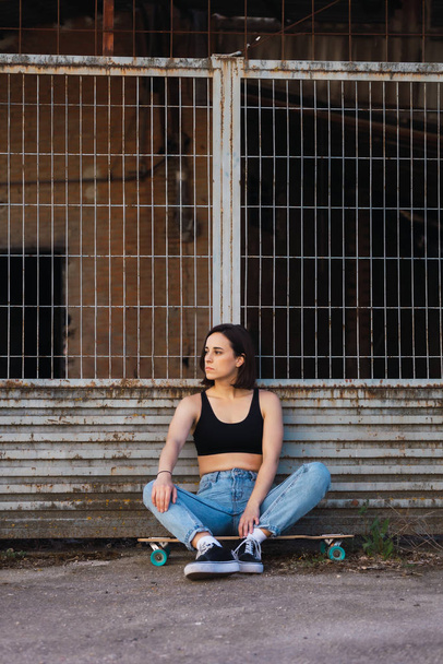 Young woman sitting on her skate in an old industrial street - Photo, Image