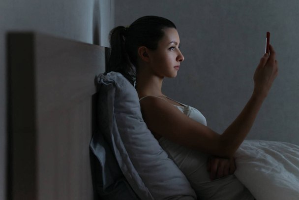 Giovane donna utilizzando il suo smartphone addictively a tarda notte in lui
 - Foto, immagini