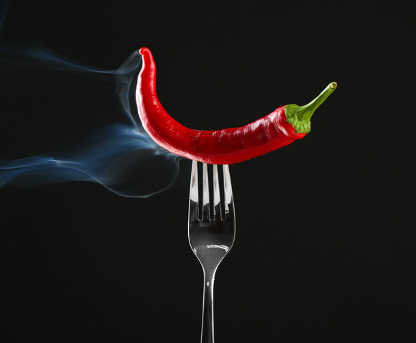 Red hot chili pepper on fork, isolated on black - Photo, Image