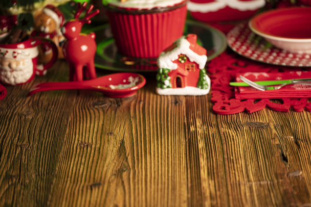 Boże Narodzenie. Świąteczne naczynia i dekoracje. Czerwone i brązowe kolory. Rustykalne drewniane tło. - Zdjęcie, obraz