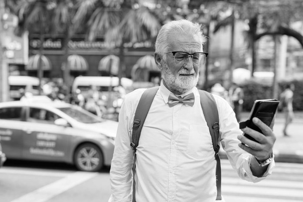 Przystojny brodaty starszy turysta zwiedzający miasto w czerni i bieli - Zdjęcie, obraz