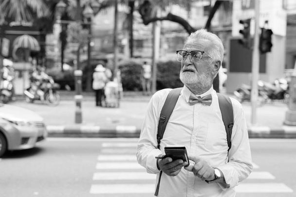 Knappe bebaarde senior toerist die de stad verkent in zwart-wit - Foto, afbeelding