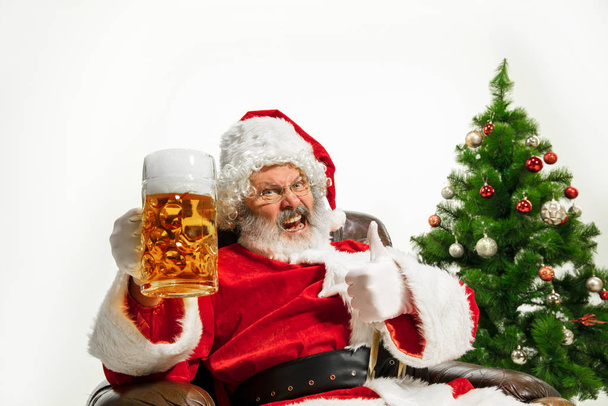 Santa Claus drinking beer near Christmas tree, congratulating of New Year 2020 - Foto, Imagen