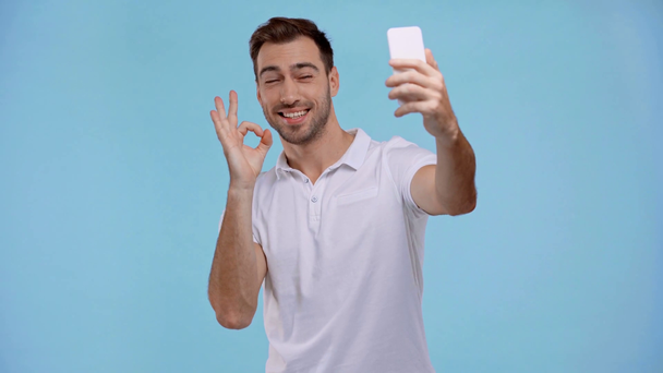 smiling man taking selfie isolated on blue  - Felvétel, videó
