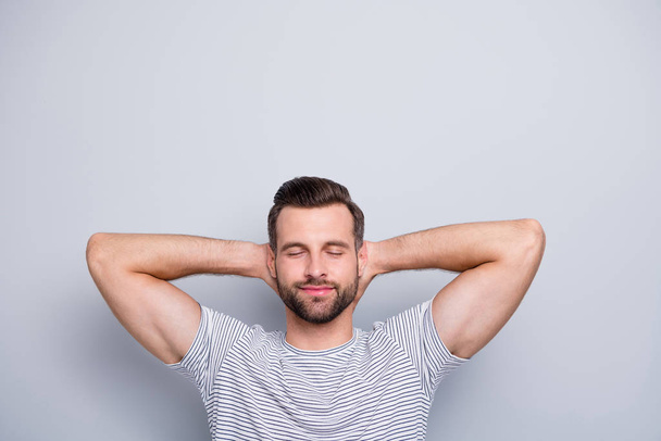 Close-up portrait of his he nice attractive muscular sportive dreamy cheery bearded guy in striped t-shirt resting closed eyes isolated over light grey pastel color background - Fotoğraf, Görsel