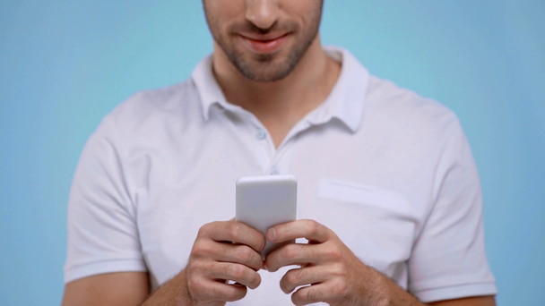 καλλιεργημένη άποψη του ανθρώπου που χρησιμοποιεί smartphone απομονωμένο σε μπλε - Πλάνα, βίντεο