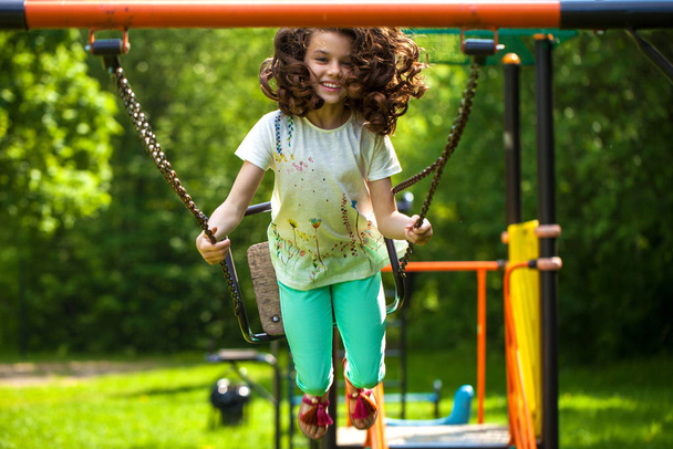 Little girl on a swing in the summer park - Foto, immagini