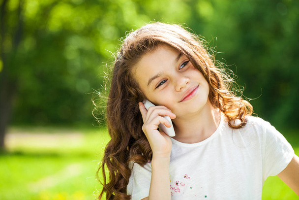 Portrait of a beautiful young little girl calling by phone - 写真・画像