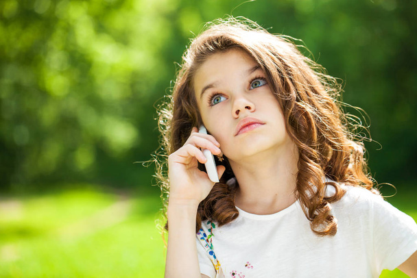 Portrait of a beautiful young little girl calling by phone - Фото, зображення