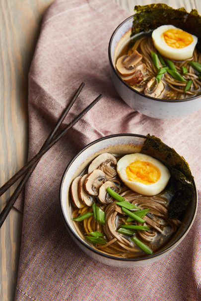traditional spicy ramen in bowls with chopsticks on wooden table with napkin - Фото, зображення