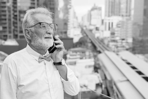 schöner bärtiger älterer Touristenmann erkundet die Stadt in Schwarz-Weiß - Foto, Bild