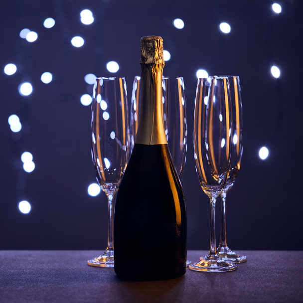 bottle of champagne and glasses with christmas lights bokeh - Zdjęcie, obraz