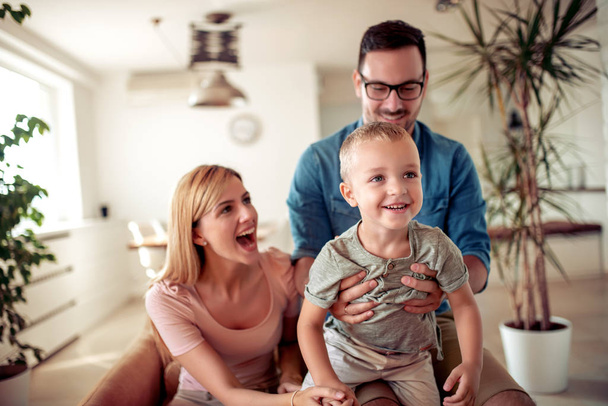 Ευτυχισμένη οικογένεια, μητέρα και πατέρας παίζουν με ένα γιο στο σπίτι. - Φωτογραφία, εικόνα