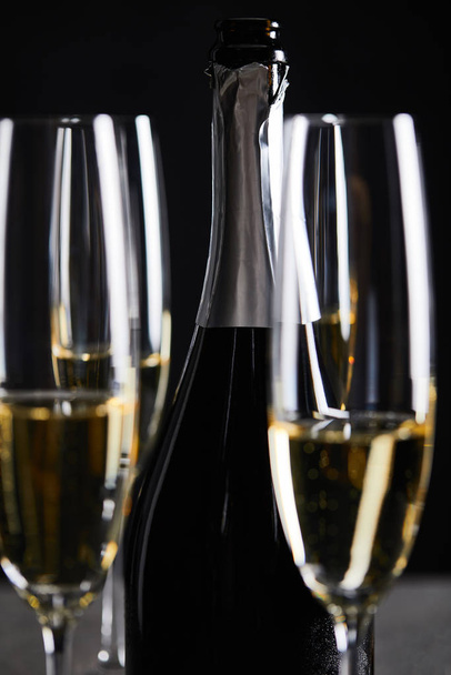 glasses and bottle of sparkling wine on black - Foto, afbeelding