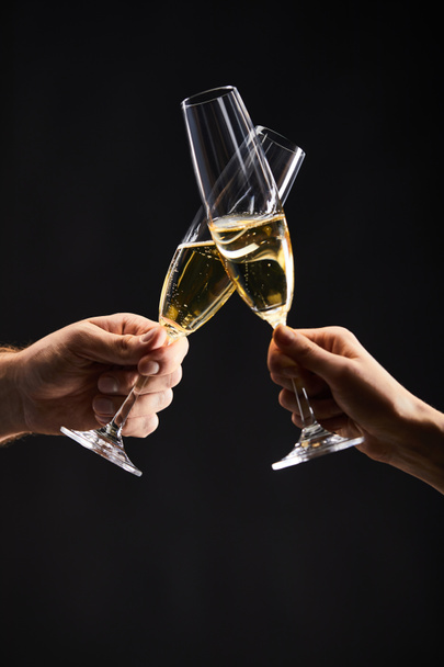 cropped view of man and woman clinking with champagne glasses and celebrating christmas, isolated on black - Photo, image