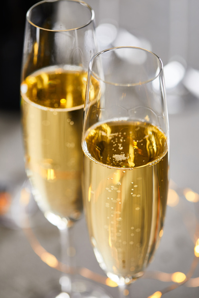 close up of glasses of sparkling wine with blurred yellow christmas lights - Fotografie, Obrázek