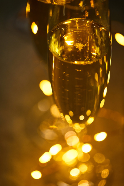 close up of glasses of sparkling wine with blurred yellow christmas lights - Zdjęcie, obraz