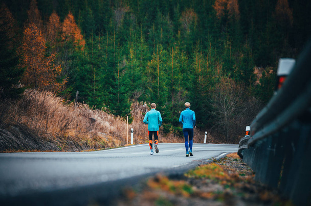 Athletes running down hill on the road - Valokuva, kuva