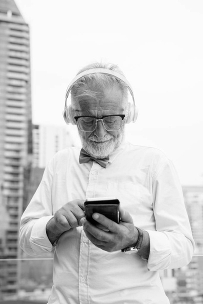 Handsome bearded senior tourist man exploring the city in black and white - Φωτογραφία, εικόνα
