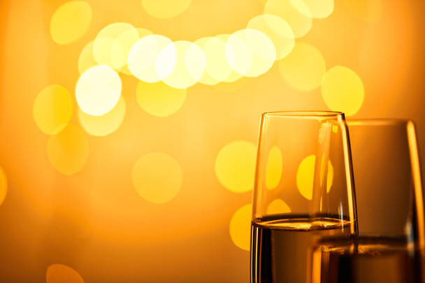 zbliżenie kieliszki szampana z żółtymi lampkami świątecznymi bokeh - Zdjęcie, obraz
