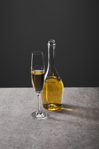 glass and bottle of sparkling wine on grey - Foto, Bild