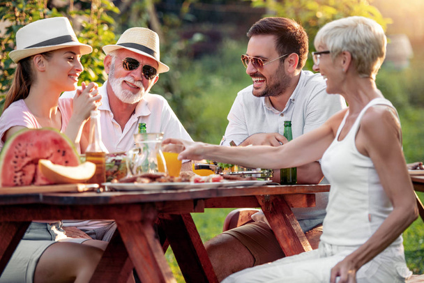 A család nyáron grillpartit tart a kertjükben. Szabadidő, élelmiszer, emberek és nyaralás koncepció. - Fotó, kép