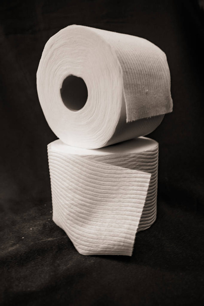 складені рулони туалетного паперу на чорному фоні
 - Фото, зображення