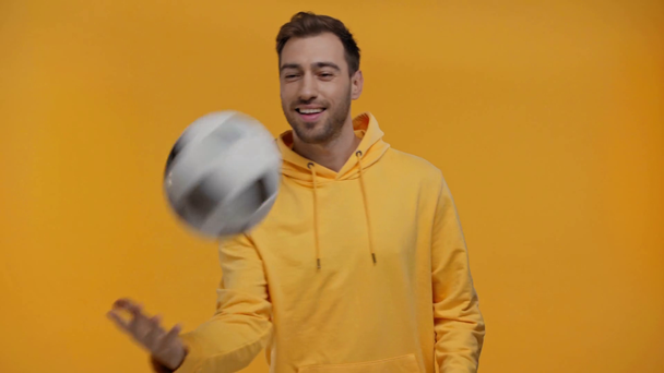 smiling man playing with football isolated on yellow - Materiał filmowy, wideo