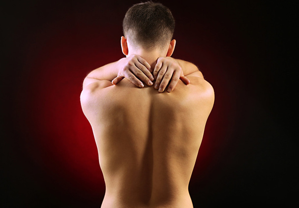 Young man with neck pain, on red background - Fotografie, Obrázek
