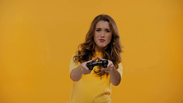 KYIV, UKRAINE - SEPTEMBER 13, 2019: woman playing video game isolated on yellow - Video, Çekim