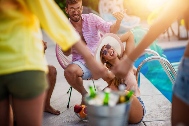 Ομάδα φίλων που κάνουν πάρτι στην πισίνα, πίνουν μπύρες και διασκεδάζουν μαζί. - Φωτογραφία, εικόνα