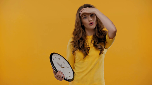 mujer conmocionada sosteniendo reloj aislado en amarillo
 - Imágenes, Vídeo