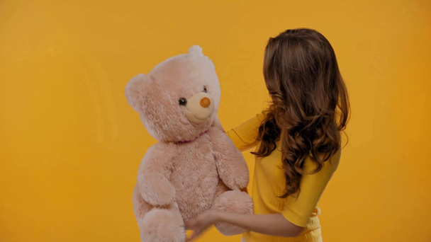 podrážděná žena mluví s medvídkem izolované na žluté - Záběry, video