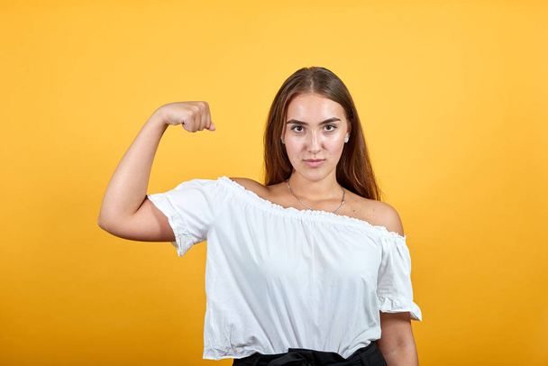 Strong charming young woman showing muscules, looking serious - Photo, Image
