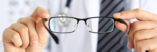Male medicine doctor hands giving pair of black glasses - Photo, Image