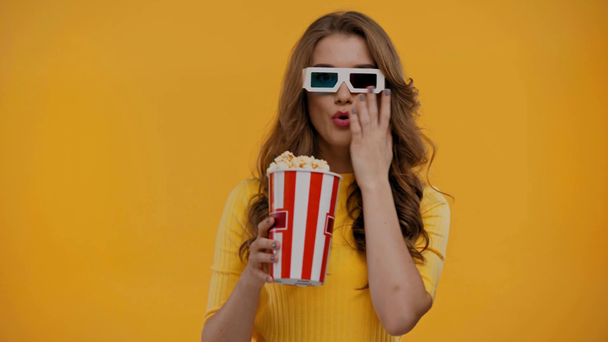 žena sleduje film a jíst popcorn izolované na žluté - Záběry, video