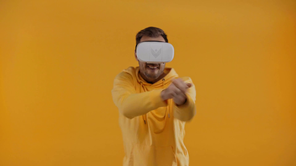 man with virtual reality headset shooting isolated on yellow - Footage, Video