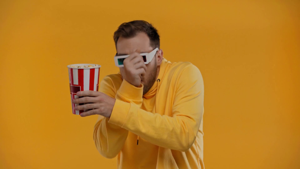 muž jíst popcorn a sledovat film izolované na žluté - Záběry, video