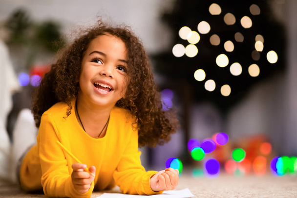 Dreamy african child writing wishlist for Christmas holidays - Photo, Image