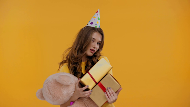 woman dancing with gifts and teddy bear isolated on yellow - Footage, Video