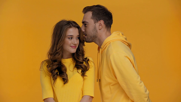 boyfriend telling secret to girlfriend isolated on yellow - Video, Çekim
