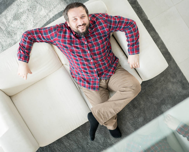 Relaxed man sitting on sofa at home - top view - Foto, imagen