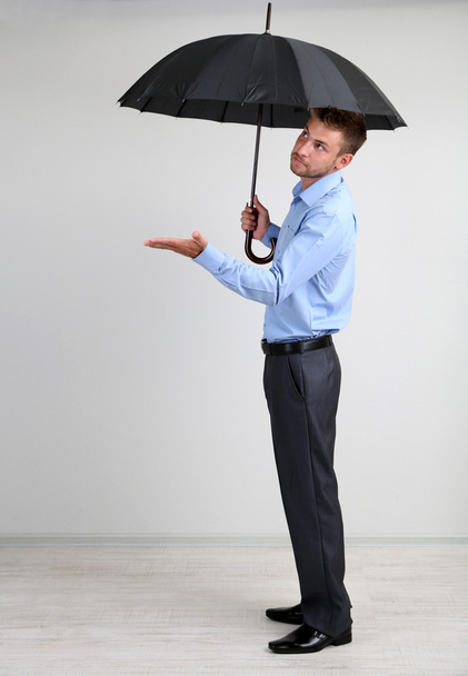 Empresario con paraguas. sobre fondo gris
 - Foto, imagen
