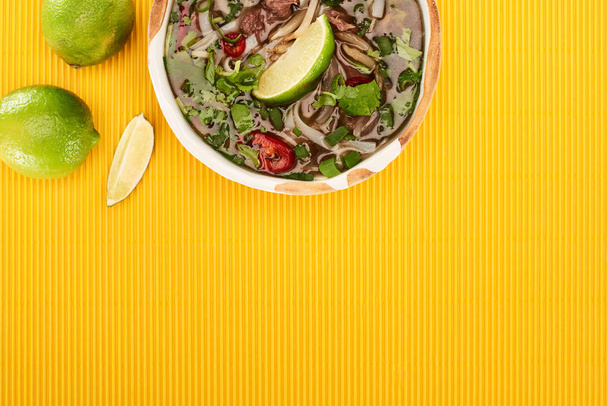top view of pho in bowl near lime on yellow textured background - Photo, Image